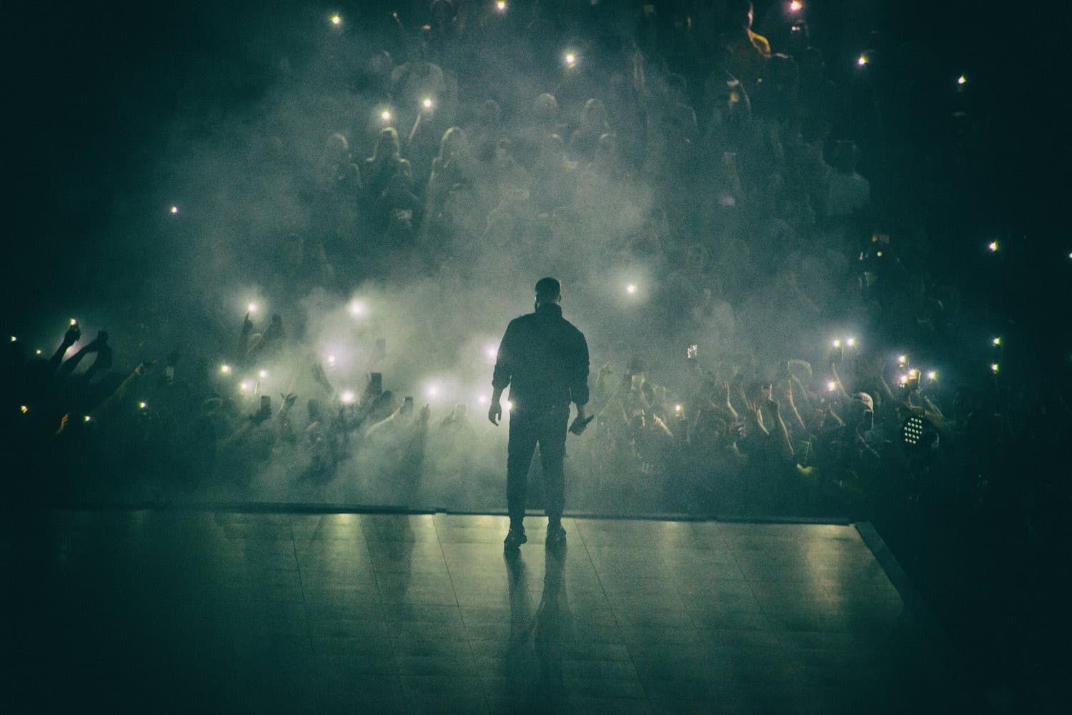 Concert silhouette facing a crowd of phone lights